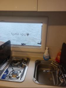 eine Küchentheke mit einem Waschbecken und einem Fenster in der Unterkunft Tagoja Caravanboat Stay in Tongyeong