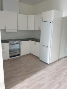 a white kitchen with white cabinets and a refrigerator at The old school motell & lägenheter in Marma