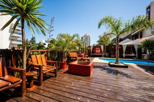 a deck with chairs and palm trees and a pool at Hostel 32 in Punta del Este