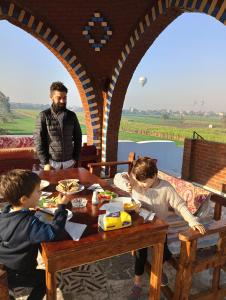 un homme assis à une table avec deux enfants mangeant de la nourriture dans l'établissement Villa Colossi Memnon, à Louxor