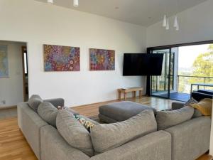a living room with a couch and a flat screen tv at Hill Top Retreat in Nubeena