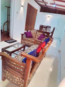 uma sala de estar com cadeiras de madeira e uma mesa de vidro em Araliya Uyana Residencies Colombo - Entire House with Two Bedrooms em Colombo