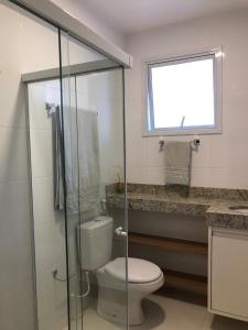 a bathroom with a toilet and a glass shower at Studio Completo, Condominio Grand Smart Residence in Aracaju