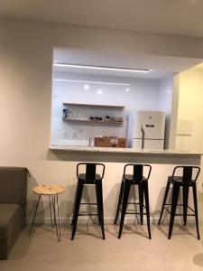 a kitchen with four bar stools and a counter with a refrigerator at Studio Completo, Condominio Grand Smart Residence in Aracaju