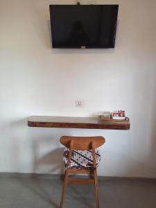 a wooden table with a chair and a television on a wall at ZEN MOON Hostel in Yogyakarta
