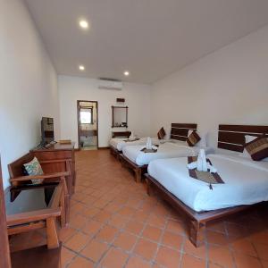 eine Gruppe von 4 Betten in einem Zimmer in der Unterkunft Villa Chitchareune 2 in Luang Prabang