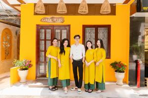 a group of people standing in front of a yellow building at Celine House in Ho Chi Minh City