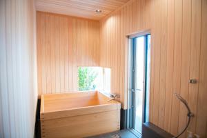 baño con bañera de madera y ventana en 木を楽しむ一棟貸しの宿「ウッドヴィラ 心楽 -SHIGURA-」, en Tamba