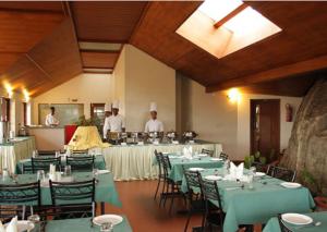 钦纳卡纳Ayur County Resort的一间设有桌子的用餐室,后面有人