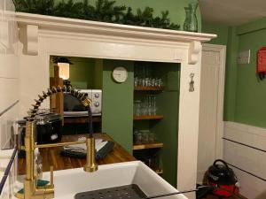 eine Küche mit grünen Wänden, einer Spüle und einer Uhr in der Unterkunft 22 in Érin