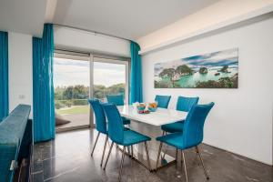 uma sala de jantar com uma mesa branca e cadeiras azuis em Protaras Beachfront Thalassa Suite em Protaras