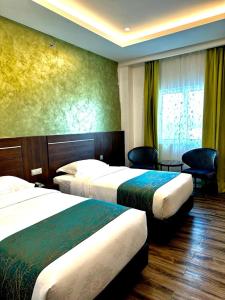 Habitación de hotel con 2 camas y 2 sillas en Malibest Resort en Pantai Cenang
