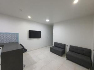 una sala de espera con 2 sofás y TV de pantalla plana en Durango Life, en Durango