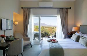 a hotel room with a bed and a table and a window at Sugarbird Manor in Stellenbosch