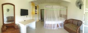 un soggiorno con letto, tavolo e specchio di Sinharaja Hostel 114 a Deniyaya