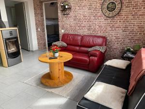 a living room with a red couch and a table at Gîte en Baie de Somme in Saint-Blimont