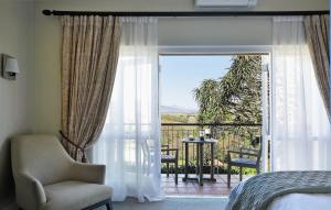 a bedroom with a bed and a chair and a balcony at Sugarbird Manor in Stellenbosch