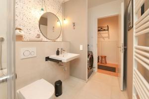 ein weißes Badezimmer mit Waschbecken und Spiegel in der Unterkunft Blue Chili 33 - Modernes & gemütliches Business Apartment am Airport BER in Schönefeld + 14 Fotos