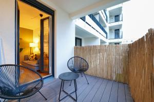 einen Balkon mit zwei Stühlen und einem Zaun in der Unterkunft Blue Chili 33 - Modernes & gemütliches Business Apartment am Airport BER in Schönefeld