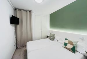 a bedroom with a white bed and a television at Aptos La Costera in Benidorm
