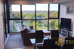 a living room with a couch and a large window at Lovely in Lyneham - 1bd 1bth Apt in Canberra