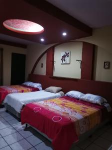 2 Betten in einem Zimmer mit rot und gelb in der Unterkunft Apartamento Central Xelajú in Quetzaltenango