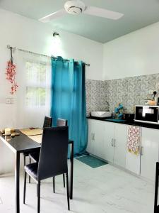 a kitchen with a table and a blue curtain at Amore Apartment, Maldives in Dhangethi