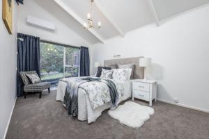 a white bedroom with a bed and a window at The Hidden Clifftop Gem - Beach life - North Shore in Auckland