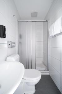 La salle de bains blanche est pourvue d'une douche et de toilettes. dans l'établissement Hotel Goldener Stern - contactless check-in, à Lucerne