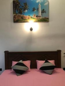 ein Bett mit rosa und schwarzen Kissen und einem Leuchtturm in der Unterkunft Villa Amorino in Galle