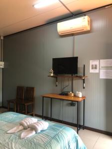 a bedroom with a bed and a desk with a television at โรงแรมกรีนแฮปปี้โฮมสเตย์ in Ban Hua Khot