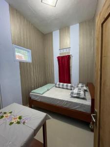 um pequeno quarto com uma cama e uma toalha vermelha em Villa Cakrawala em Tawangmangu