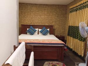 een slaapkamer met een bed met blauwe kussens en een ventilator bij Ella Relax Inn in Ella
