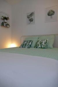 a bed with green sheets and pillows on top of it at Disneyland Paris 70m² face Parc, place Ariane in Serris