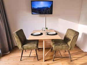 een houten tafel met twee stoelen en een tv aan de muur bij Alpen Studio Ellmau II in Ellmau