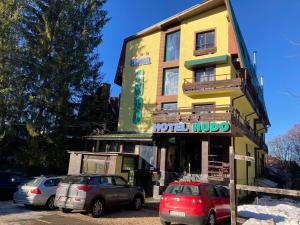 ein gelbes Gebäude mit davor geparkt in der Unterkunft Hotel Rudo in Predeal