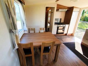Gilcrux的住宿－Lake District Solway View 16 The Beeches Caravan Park，厨房以及带木桌和椅子的用餐室。