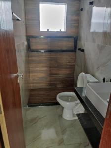 Un baño con inodoro, lavabo y ventana. en Oceano Residence, en Búzios