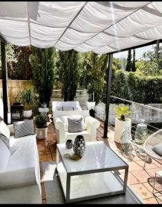 un patio con muebles blancos y una sombrilla blanca en Estilosa casa golf, en Gorraiz