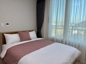 ein Schlafzimmer mit einem großen Bett und einem großen Fenster in der Unterkunft Eunhasu D&M Residence Cheongcho 3 in Daejeon