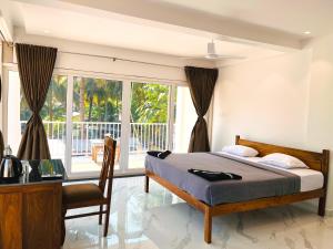 Schlafzimmer mit einem Bett, einem Schreibtisch und einem Fenster in der Unterkunft Crystall Goa Palolem in Palolem