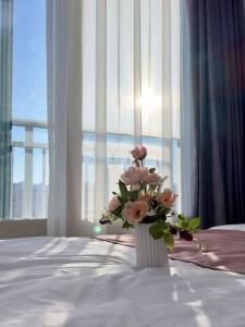 un jarrón de flores sentado en una cama con una ventana en Eunhasu D&M Residence Cheongcho 4, en Daejeon