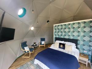 a bedroom with a bed and a tv and chairs at Benllech Glamping in Benllech
