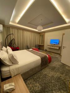 Habitación de hotel con cama grande y TV en فندق جولدن توليب أبها - GOLDEN TULIP ABHA HOTEl, en Abha