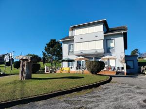 una gran casa blanca con césped delante en Hotel Capellan, en Navia