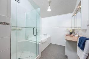 a bathroom with a glass shower and a sink at The Hidden Clifftop Gem - Beach life - North Shore in Auckland