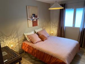 een slaapkamer met een bed met kussens erop bij Latitude Savoie in Drumettaz-Clarafond