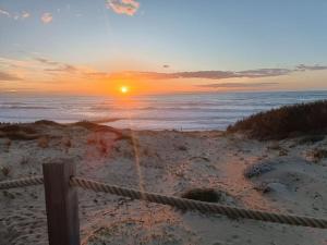 a sunset over the ocean with a fence on the beach at Appartement T2, proche de la mer in Seignosse