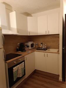 a kitchen with white cabinets and a sink and a stove at Appartement T2, proche de la mer in Seignosse