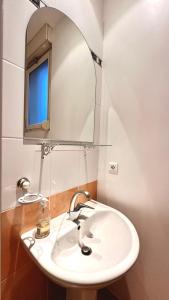 W łazience znajduje się biała umywalka i lustro. w obiekcie Gîte rural Le Péché Mignon w mieście Lignol-le-Château